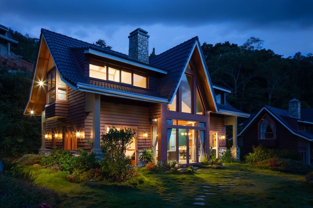 A wooden house with lights outside in the middle of the night.