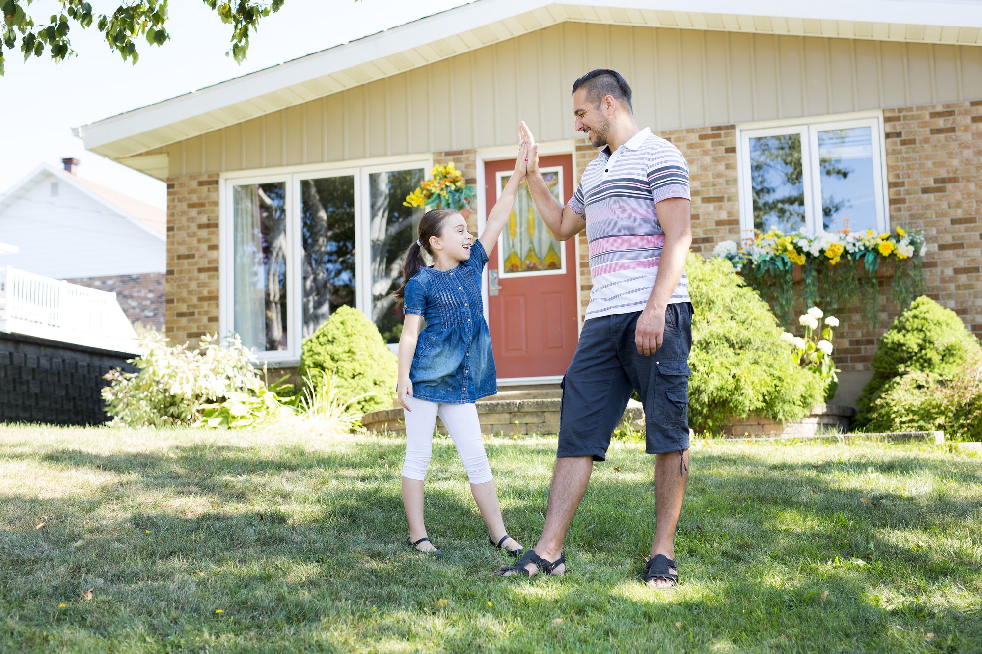 Father and daughter in front of a house.