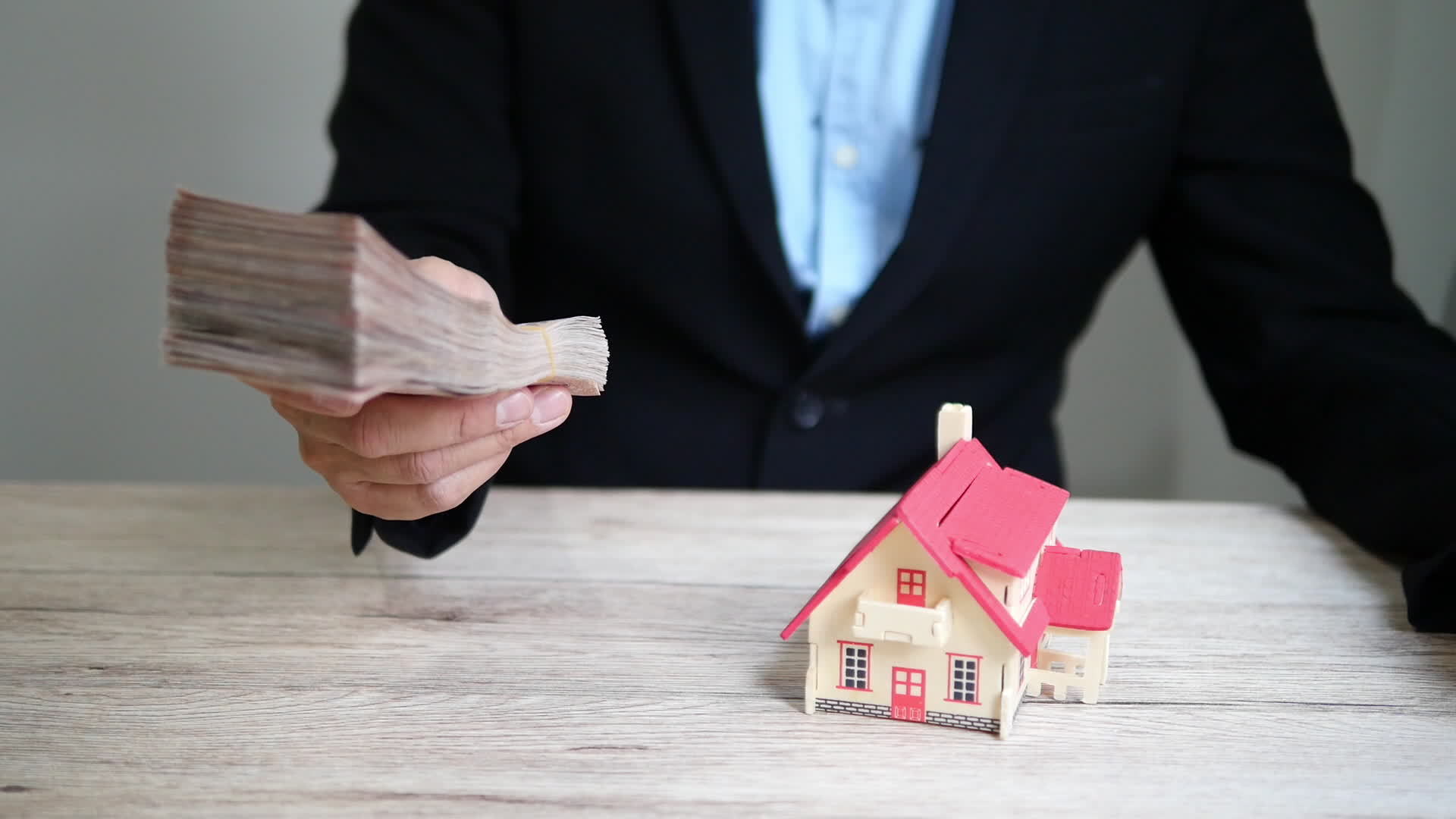 A man hands a wad of cash for a house.