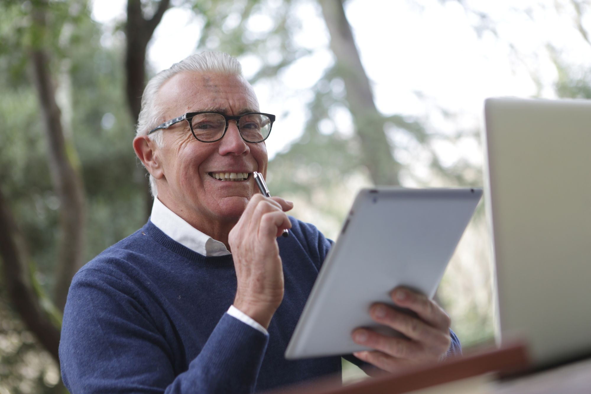 An elderly man with a tablet and a laptop.