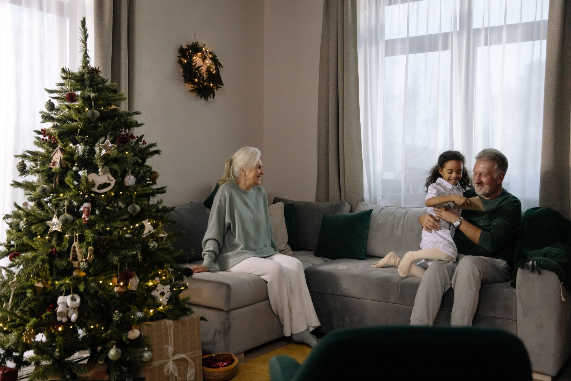 An elderly couple with a young girl during Christmastime.