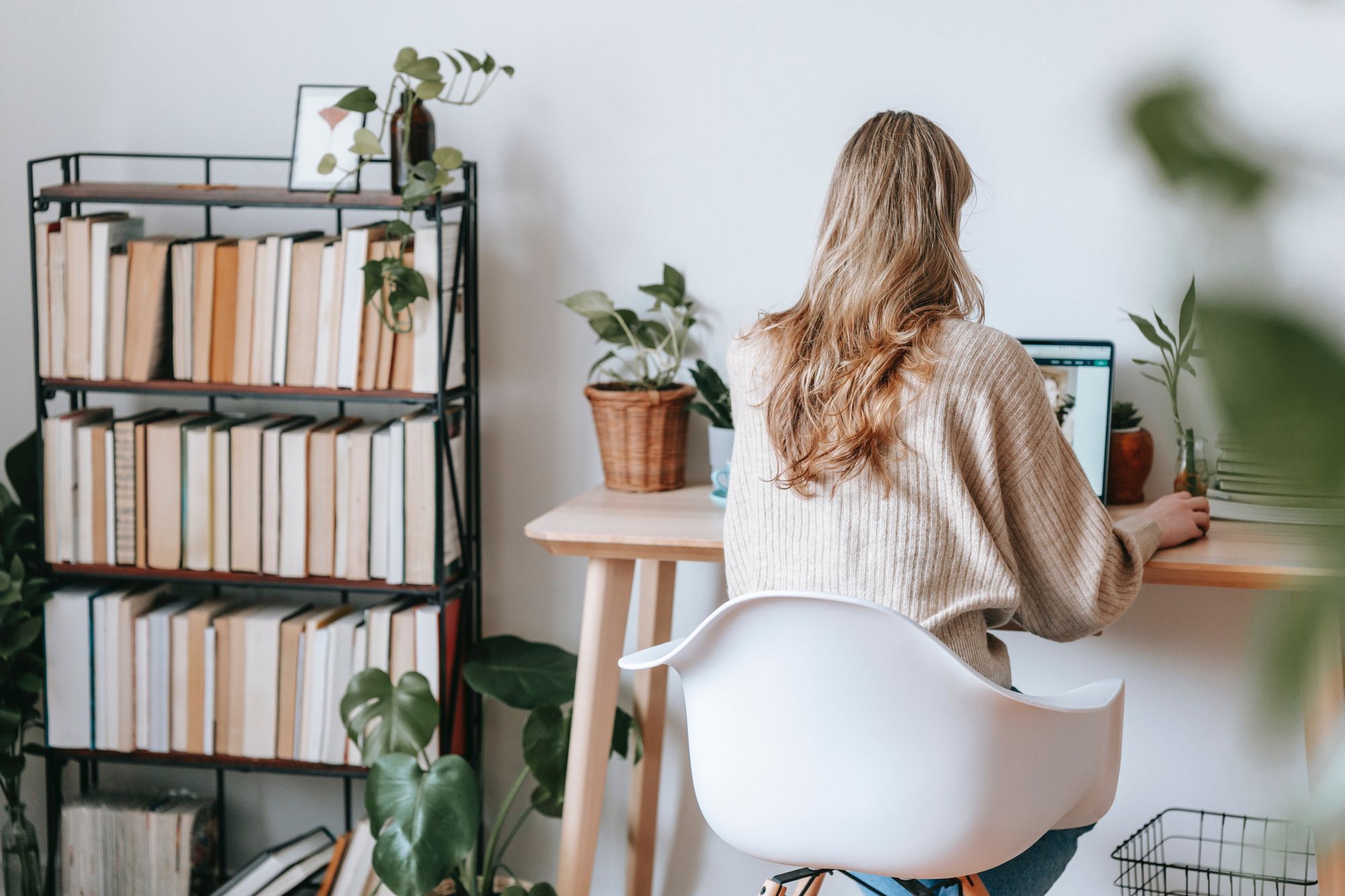 A woman in her home office with a bookshelf beside her desk.