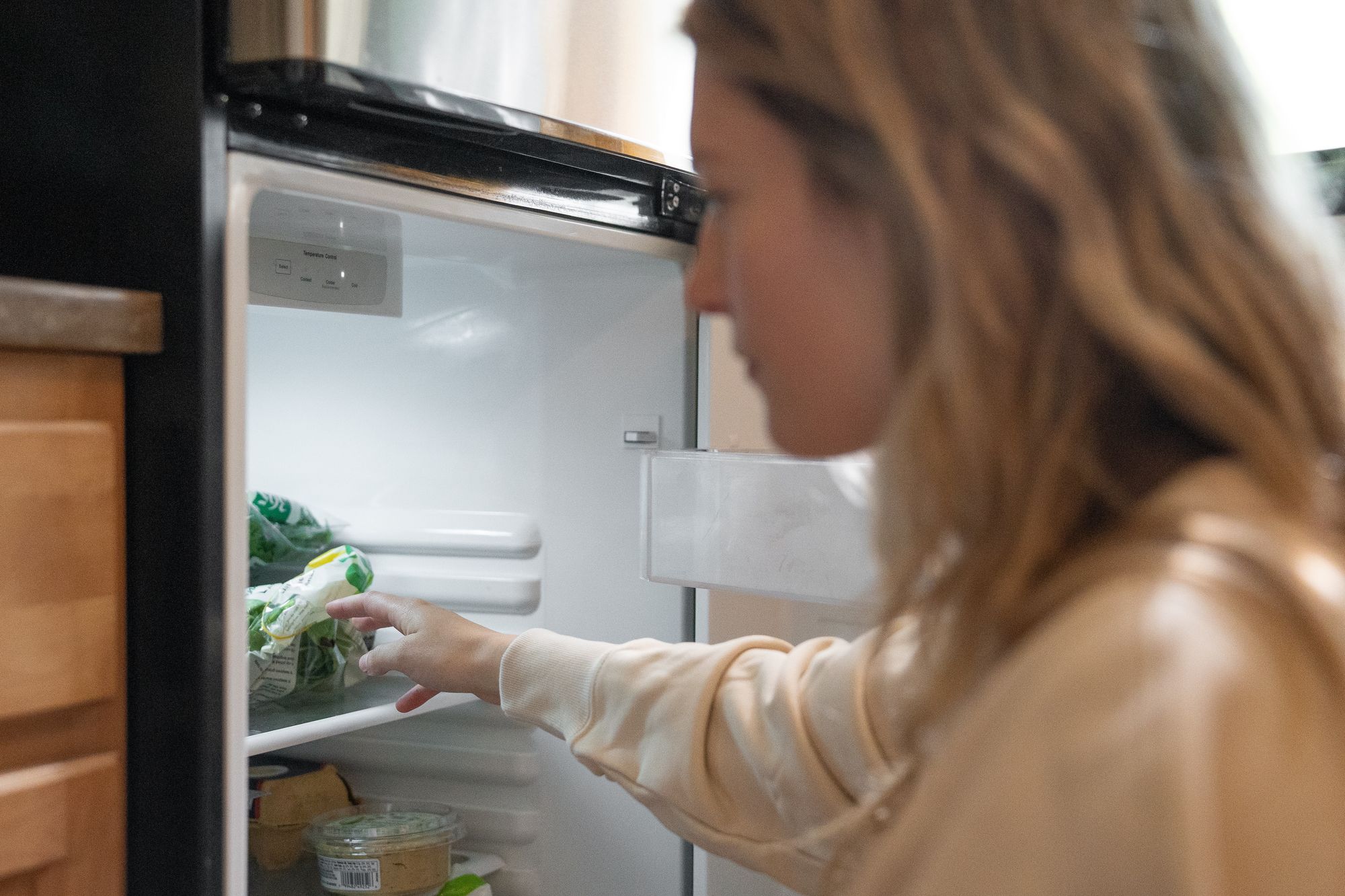 A woman opening a refrigerator.