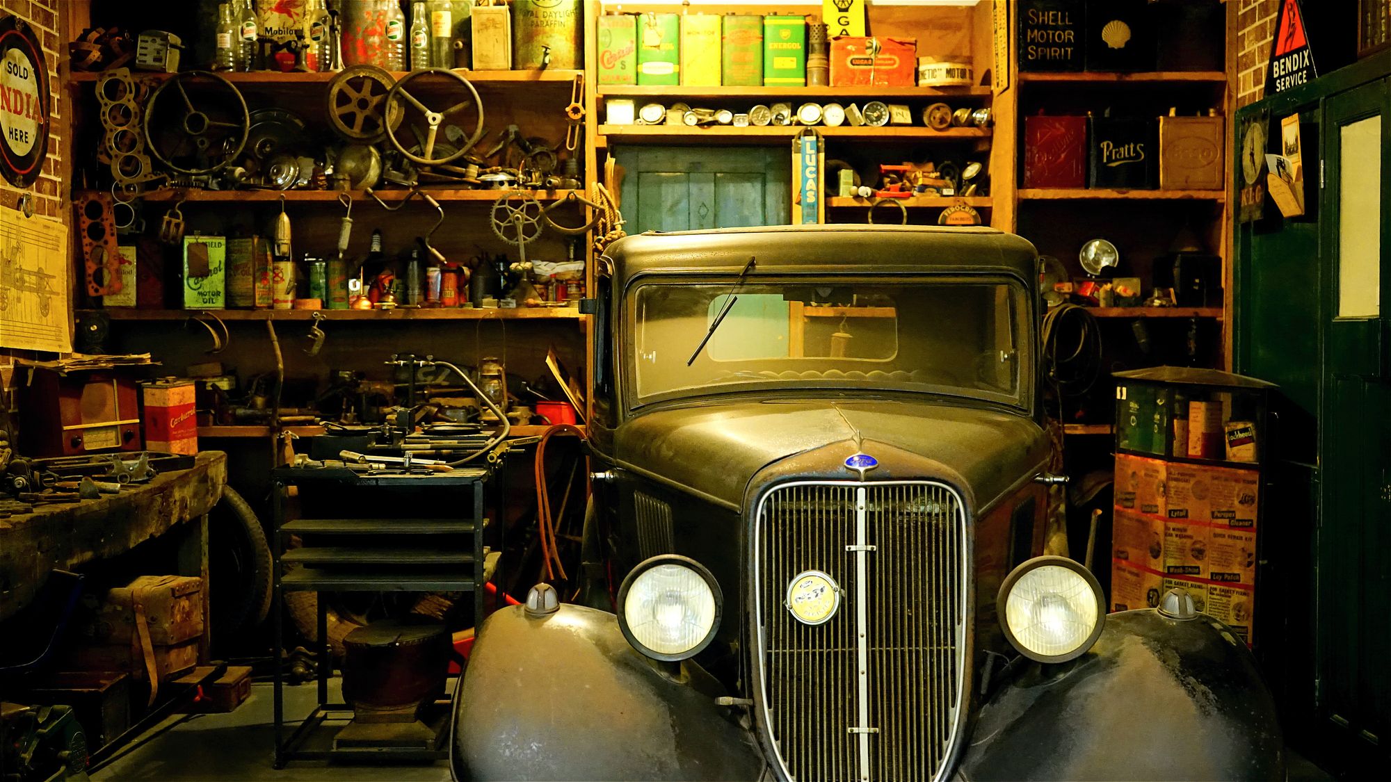 An old garage with a vintage car and auto supplies.